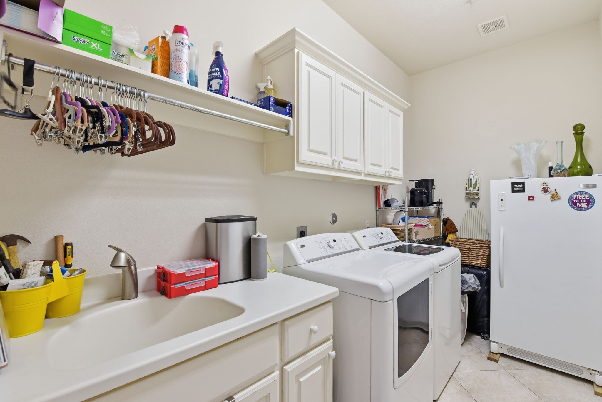 223 South Bauer Point Circle Spring, TX 77389 - Photo 22 of 50 This laundry room features a spacious layout with a washer and dryer, a utility sink, ample cabinetry for storage, and a hanging rod for clothes. There's also additional shelving and a refrigerator, providing extra convenience.