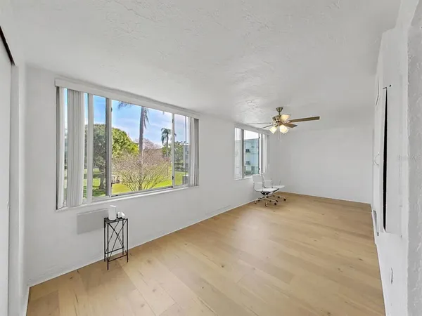 a view of an empty room with a window and wooden floor