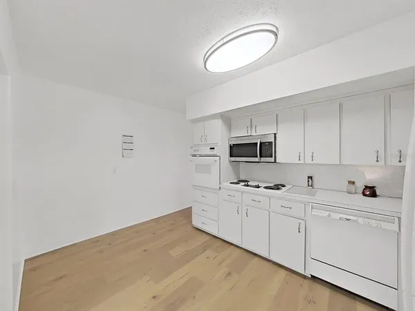 a kitchen with white cabinets and white appliances