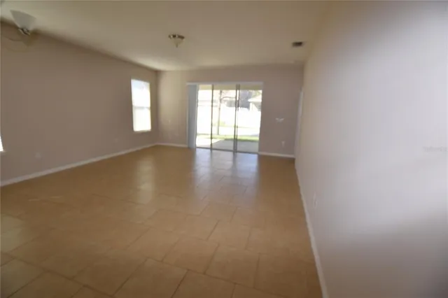 a view of an empty room with wooden floor and windows
