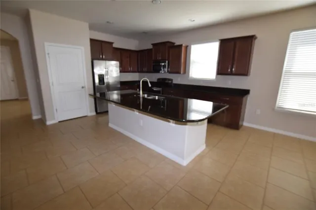 a kitchen with granite countertop a sink a stove a refrigerator and cabinets