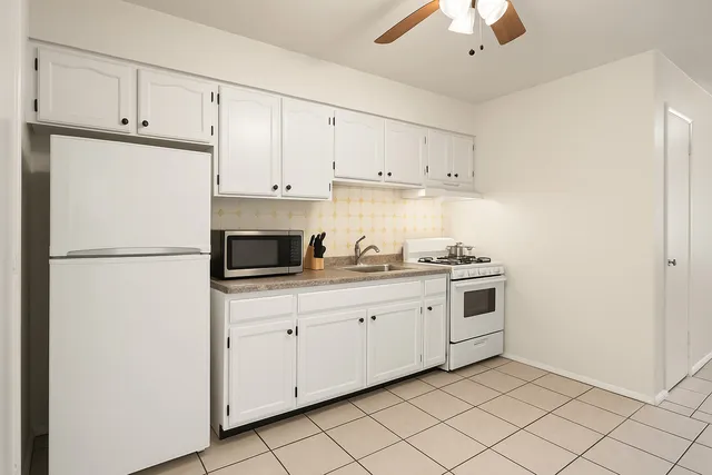 a kitchen with stainless steel appliances granite countertop a stove a refrigerator a sink a stove and white cabinets