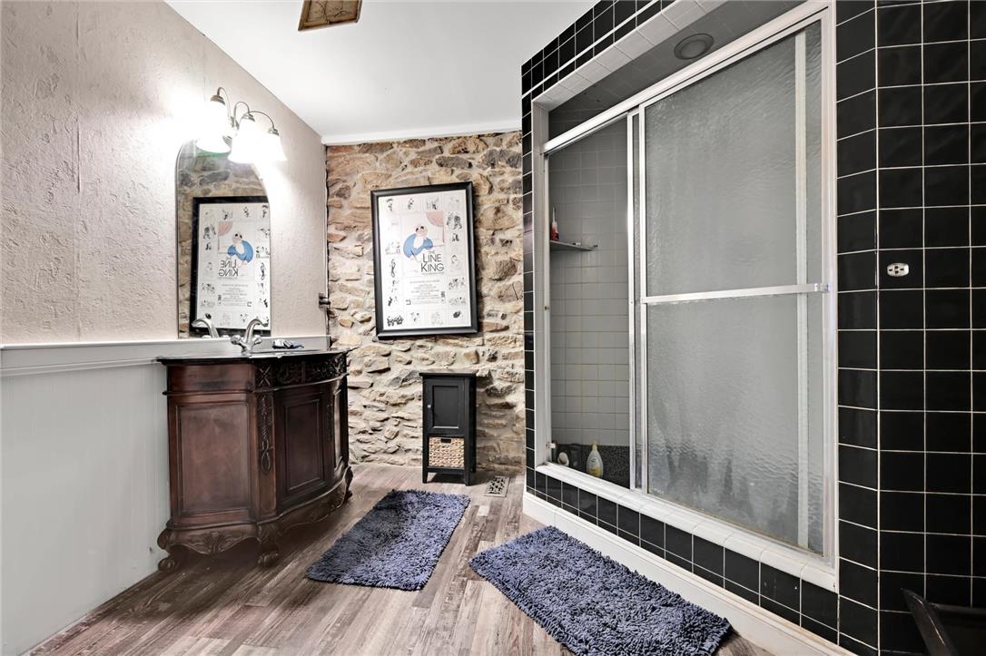 101 Conrad Road Fleetwood, PA 19522 - Photo 6 of 42 A charming bathroom with a unique blend of natural stone and smooth walls, complemented by a rustic vanity and modern shower enclosure.