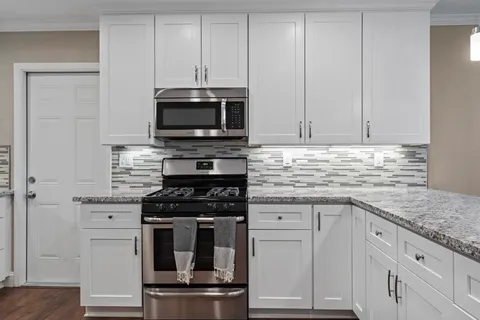 a kitchen with granite countertop white cabinets and stainless steel appliances