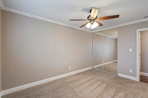 an empty room with closet and a chandelier fan