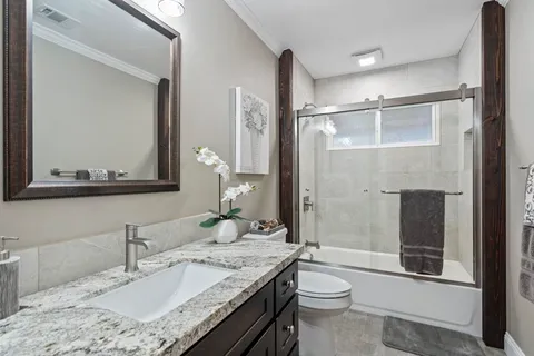 a bathroom with a granite countertop sink toilet and shower
