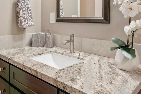 a bathroom with a granite countertop sink and a mirror
