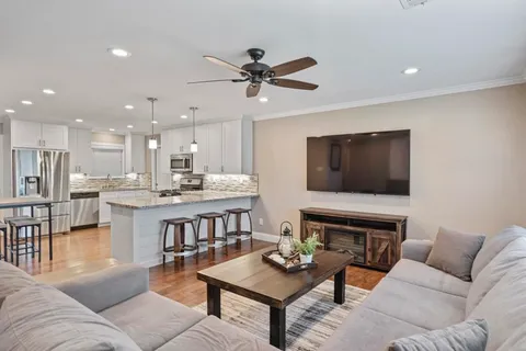 a living room with furniture kitchen view and a flat screen tv