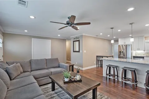 a living room with furniture kitchen view and a chandelier