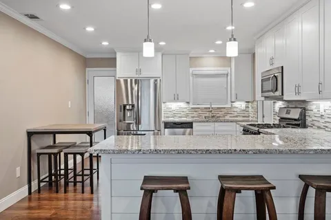 a kitchen with stainless steel appliances granite countertop a stove top oven a sink refrigerator and white cabinets