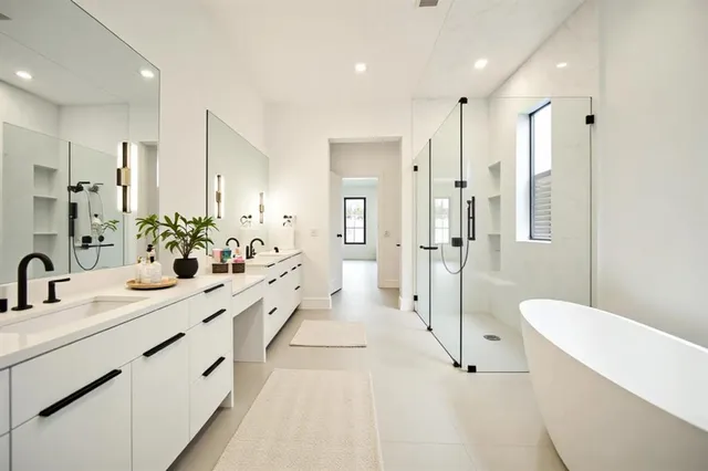 a large white bathroom with a double vanity sink a toilet a mirror and shower
