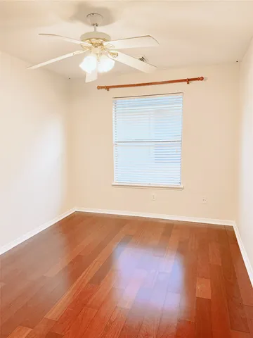 an empty room with wooden floor closet and windows