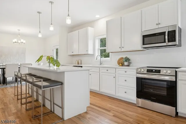 a kitchen with stainless steel appliances white cabinets a stove a sink and a microwave