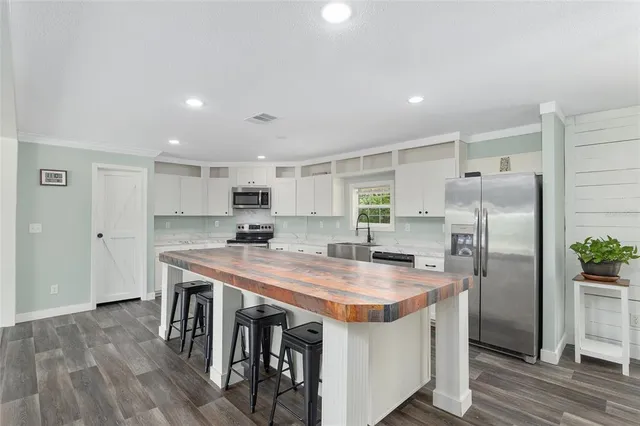 a kitchen with stainless steel appliances granite countertop a table chairs and a refrigerator