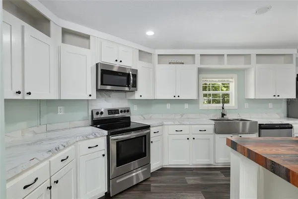 a kitchen with granite countertop white cabinets and black stainless steel appliances
