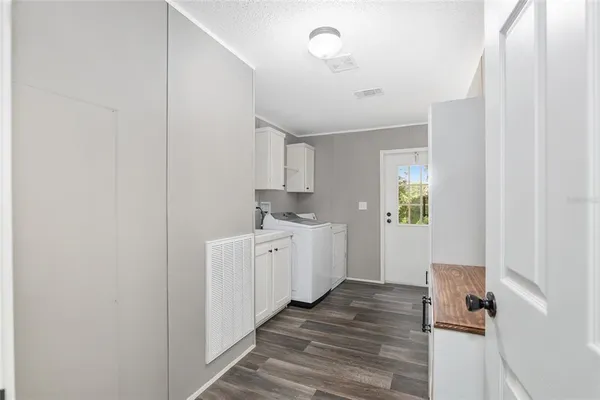 a view of a kitchen with white cabinets and wooden floor