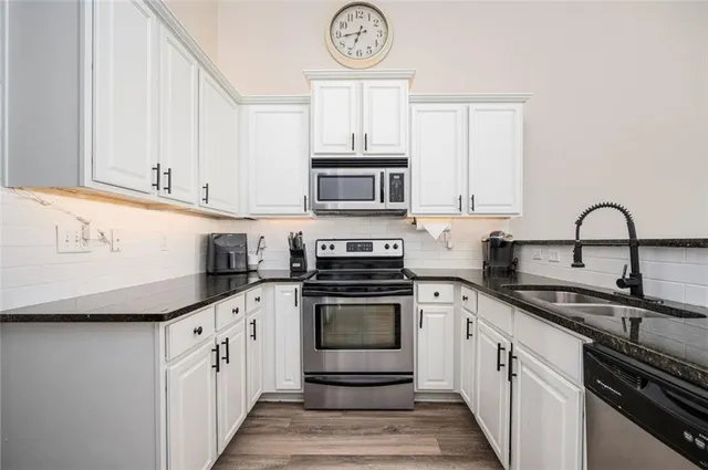 a kitchen with stainless steel appliances granite countertop a refrigerator a stove a sink and a microwave