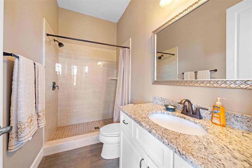 13023 Sweet Hill Road Polk City, FL 33868 - Photo 45 of 49 a bathroom with a granite countertop sink a toilet and shower