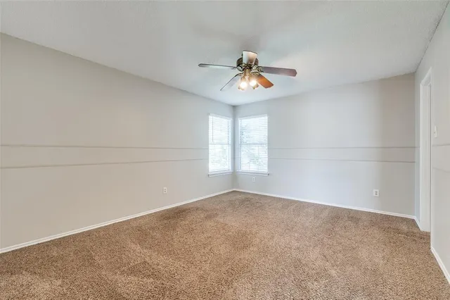 an empty room with windows and chandelier fan