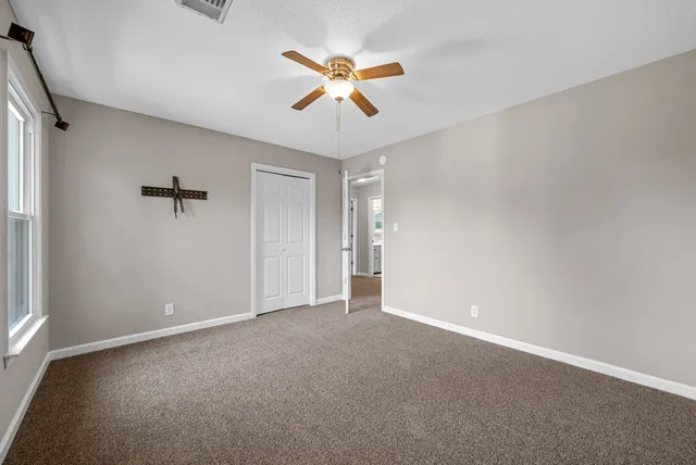 a view of an empty room with a ceiling fan and a window