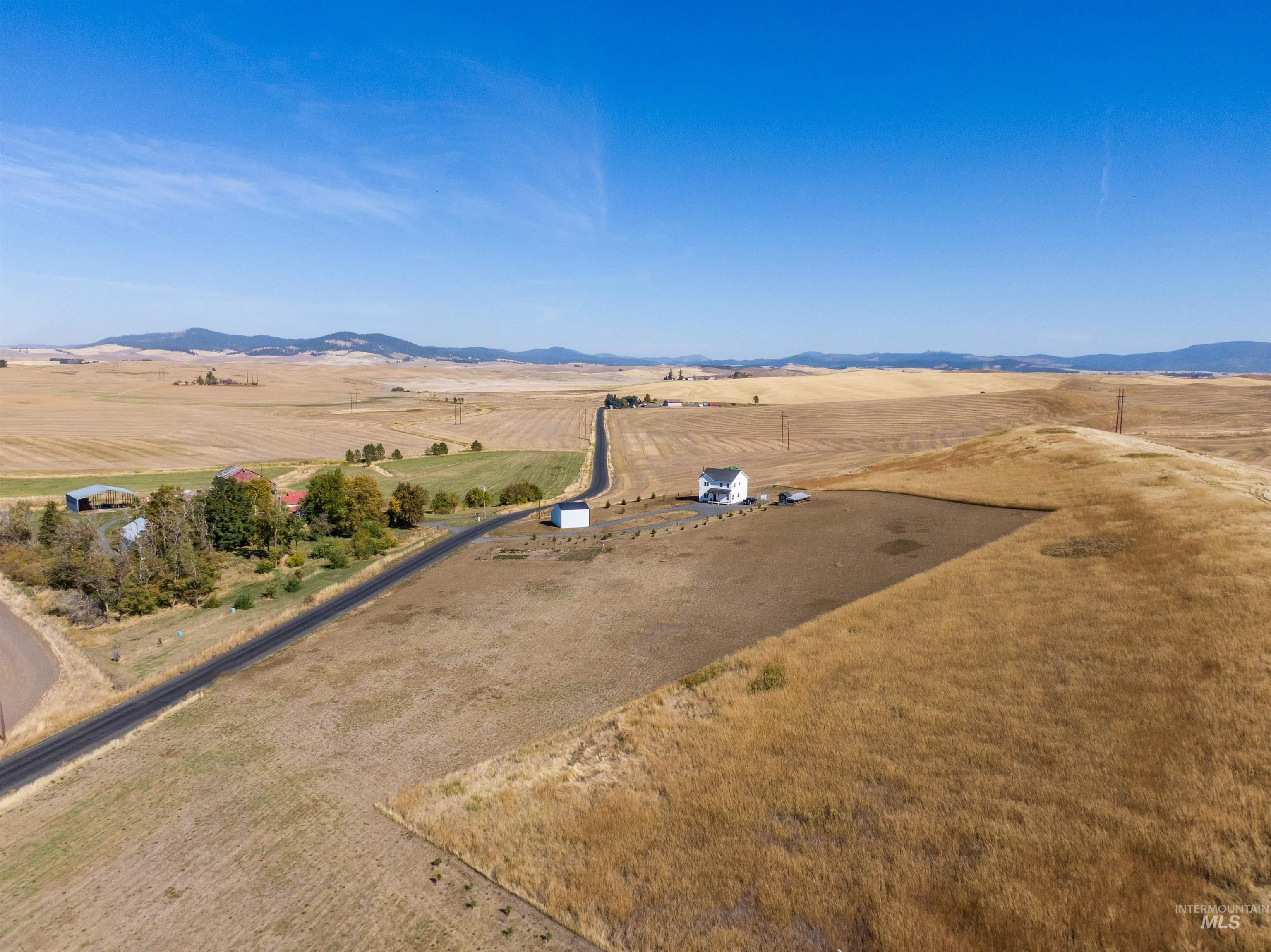 1032 Duffield Flat Road Potlatch, ID 83855 - Photo 46 of 50 Expansive rural landscape featuring a white residential structure, a paved road, and distant mountain ranges
