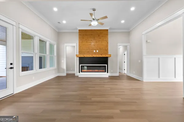 a view of an empty room with a window and wooden floor