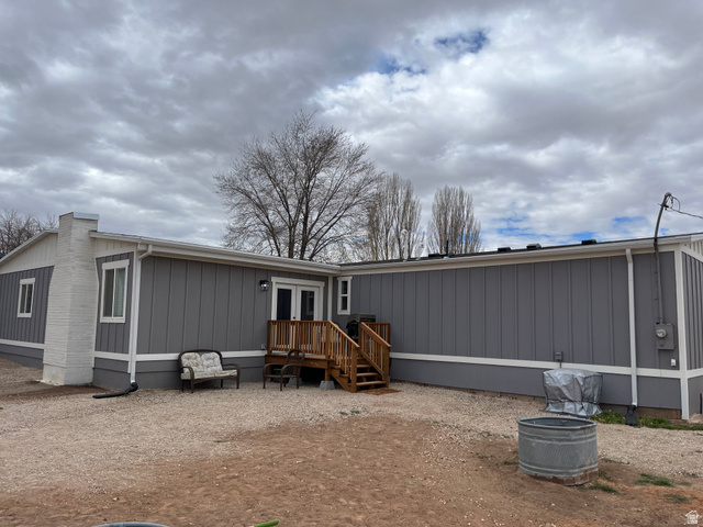 558 North N Cres Road Roosevelt, UT 84066 - Photo 4 of 31 Exterior featuring gray vertical siding, white trim, a white brick chimney, and a wooden deck with stairs