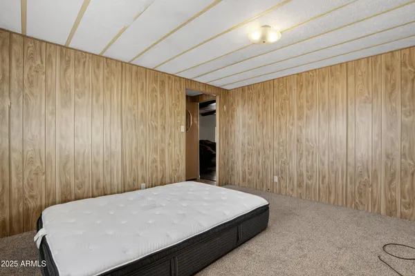 a bed sitting in a spacious bedroom next to a curtain and a window