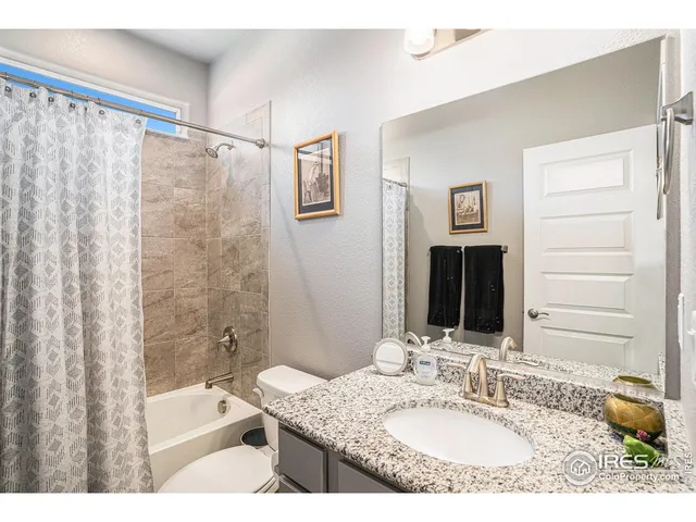 a bathroom with a granite countertop sink a mirror a bathtub and shower