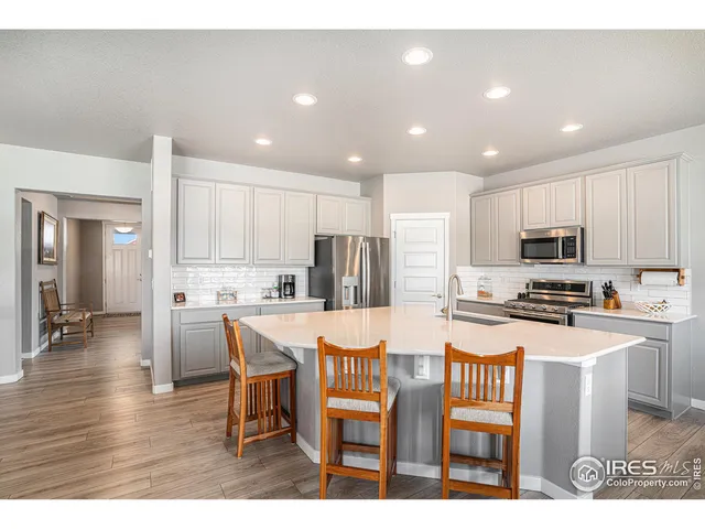 a kitchen with stainless steel appliances kitchen island granite countertop a refrigerator a stove a sink a dining table and chairs