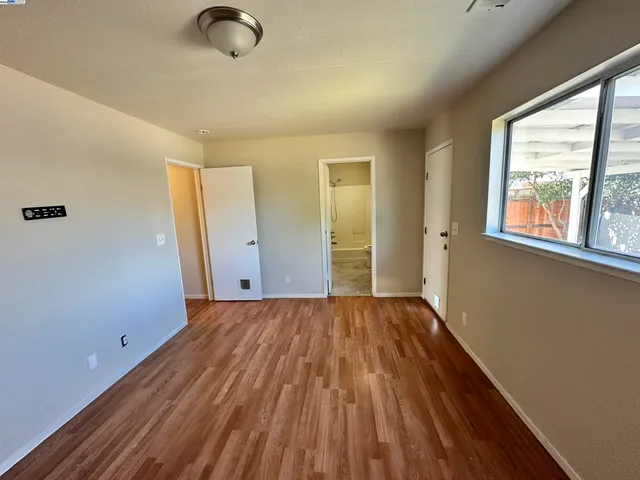a view of an empty room with wooden floor and a window