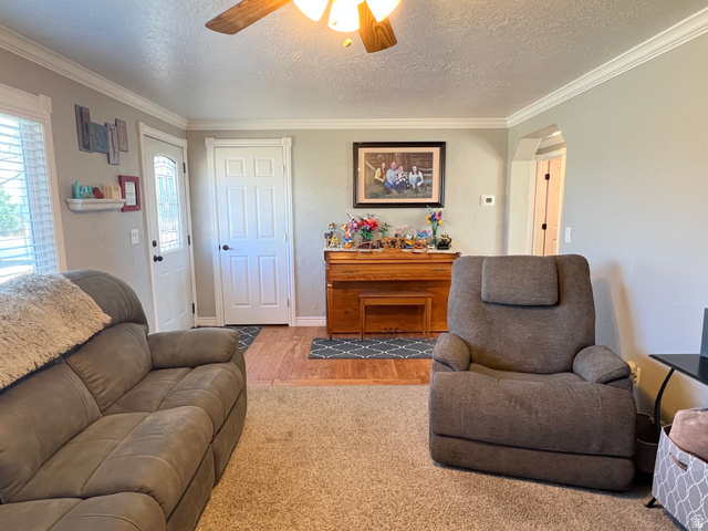 1852 East 3500th Street South Vernal, UT 84078 - Photo 8 of 46 Living area with ceiling fan, a textured ceiling, crown molding, wood finished floors, and arched walkways