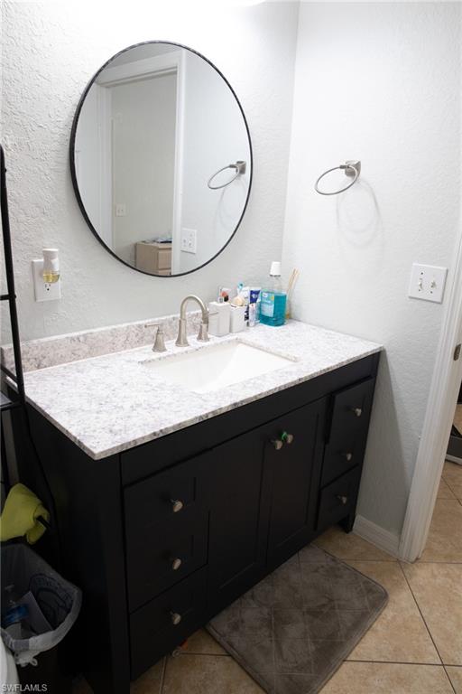 4650 St Croix Lane, Unit 726 Naples, FL 34109 - Photo 12 of 15 Bathroom with a textured wall, vanity, and light tile patterned flooring