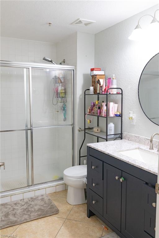 4650 St Croix Lane, Unit 726 Naples, FL 34109 - Photo 13 of 15 Bathroom featuring vanity, a shower stall, a textured wall, light tile patterned floors, and a textured ceiling