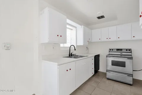 a kitchen with white cabinets a sink and a window