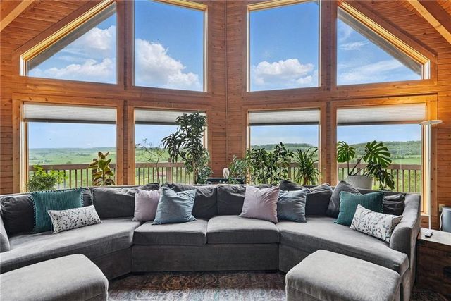 a living room with furniture large windows and a potted plant
