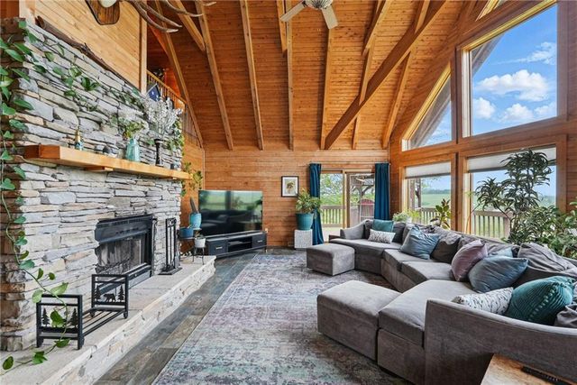 a living room with furniture a fireplace and floor to ceiling windows