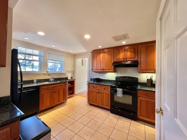 a kitchen with stainless steel appliances granite countertop a stove top oven a sink dishwasher a dining table and chairs with wooden floor