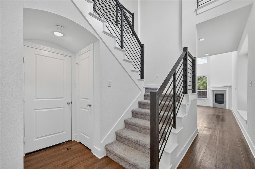 1153 Queensdown Way Forney, TX 75126 - Photo 4 of 26 Two-story foyer featuring a carpeted staircase with dark wood-finish newel posts and horizontal metal balusters, hardwood flooring, and recessed ceiling lighting