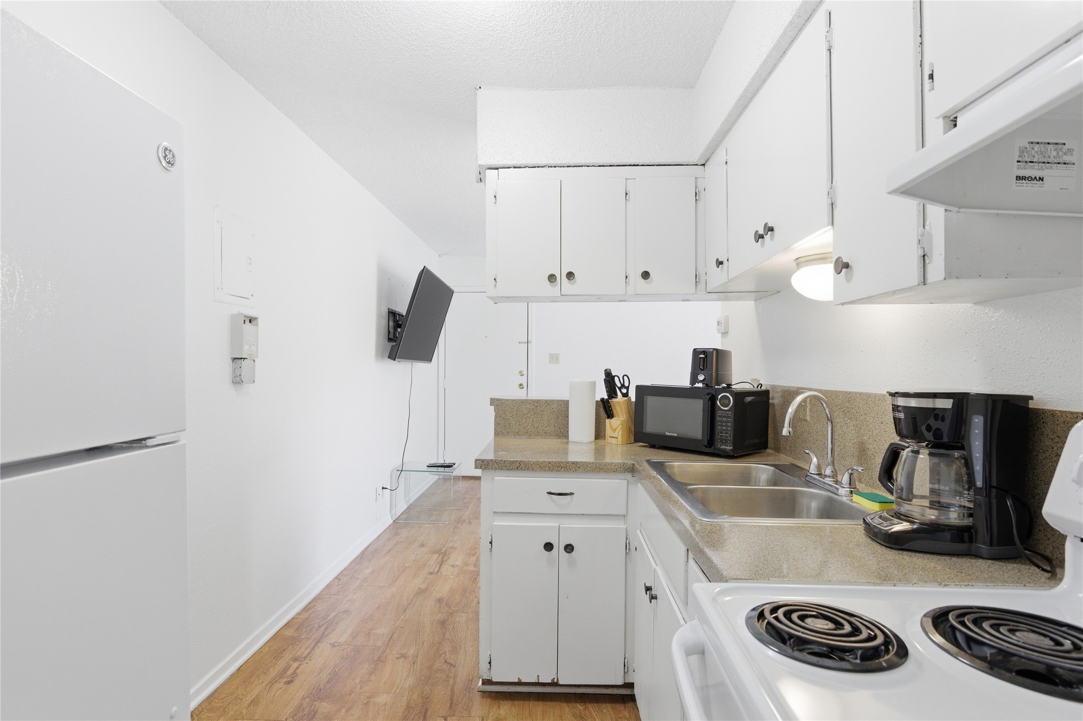 2808 Whitis Avenue, Unit C301 Austin, TX 78705 - Photo 6 of 12 a kitchen with granite countertop a sink stove and white cabinets with wooden floor