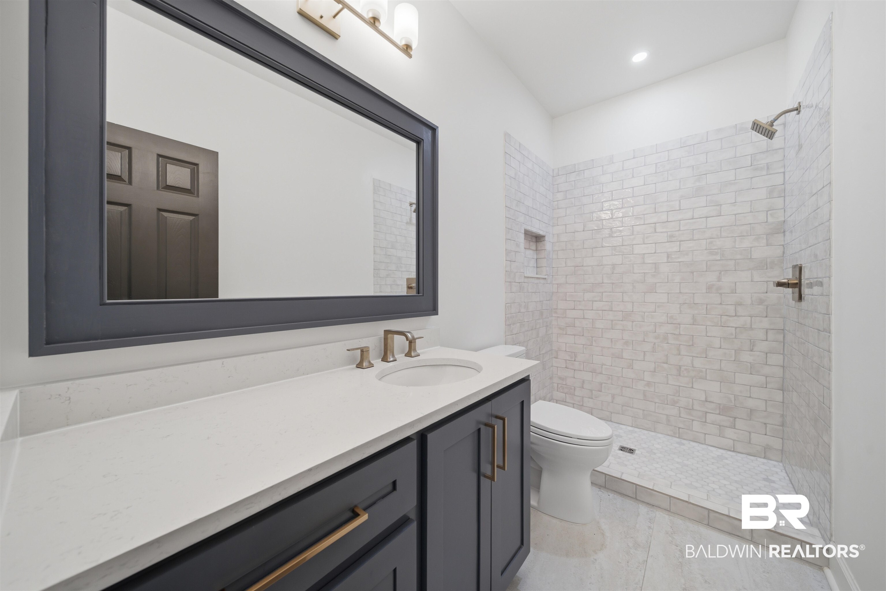 14128 Jackson Lane Foley, AL 36535 - Photo 28 of 36 Bathroom vanity featuring a light-colored countertop, undermount sink, and dark cabinetry with brushed bronze hardware