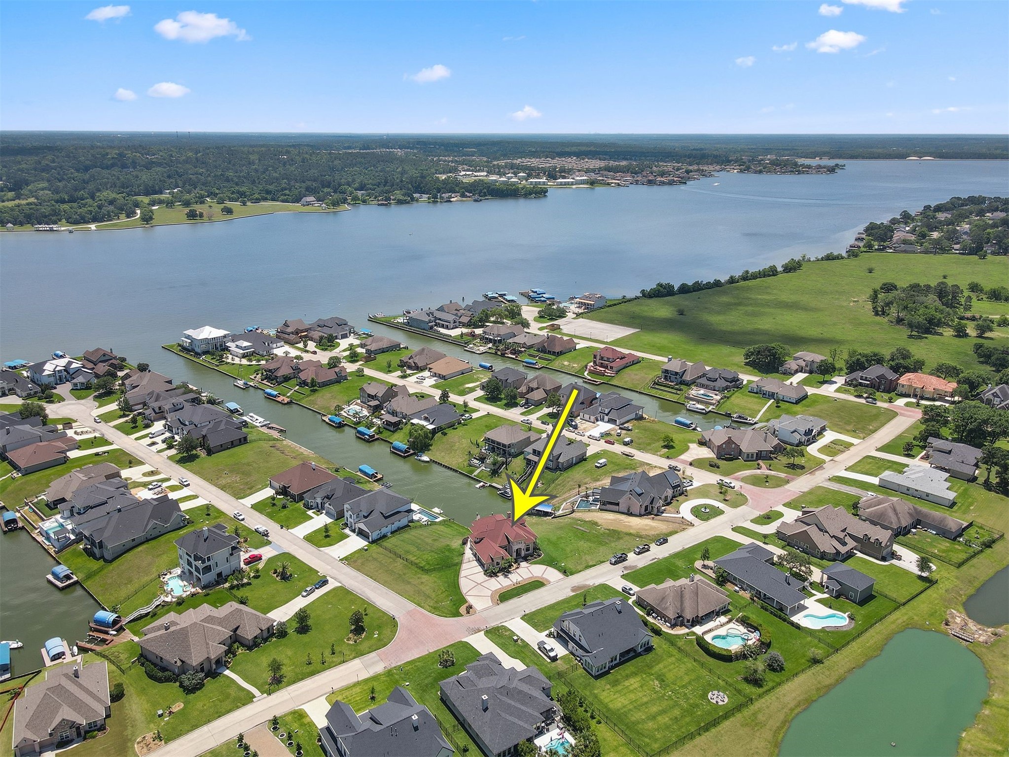 10896 Decatur Street Willis, TX 77318 - Photo 2 of 50 This aerial view captures a highlighted home in a serene waterfront neighborhood, offering stunning lake vistas, spacious properties, lush greenery, and effortless water access—a truly desirable residential haven.