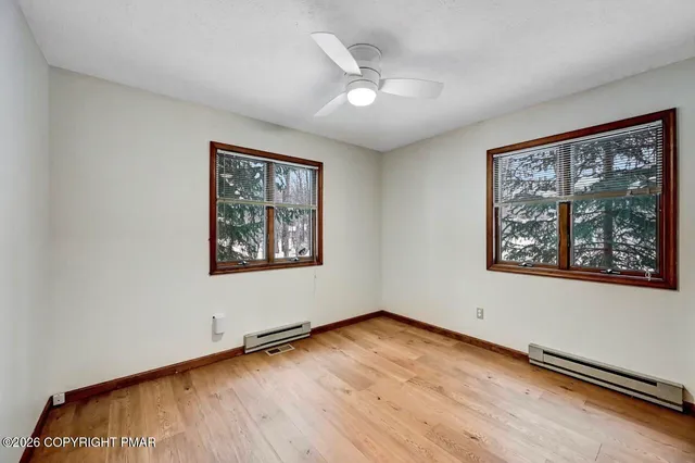 a view of an empty room with window and wooden floor