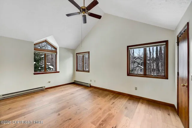 a view of an empty room with window and wooden floor