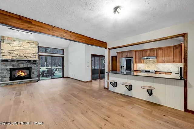 a view of an empty room with wooden floor and a fireplace