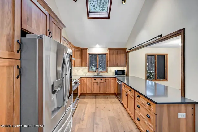 a kitchen with stainless steel appliances a refrigerator a sink dishwasher a stove and white cabinets with wooden floor