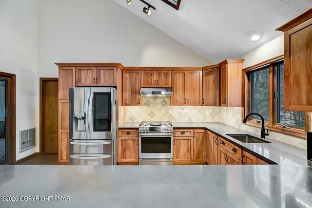 a kitchen with stainless steel appliances granite countertop a sink and a refrigerator