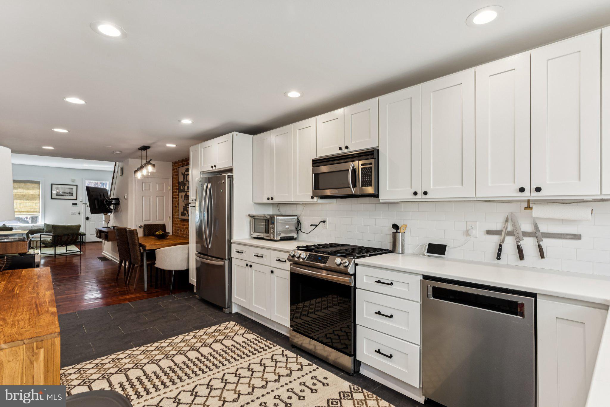 3005 Poplar Street Philadelphia, PA 19130 - Photo 19 of 53 a kitchen with stainless steel appliances granite countertop a refrigerator a sink dishwasher and white cabinets with wooden floor