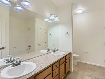 a bathroom with a granite countertop sink a large mirror and a toilet