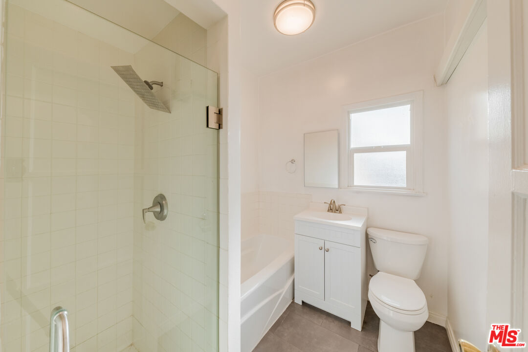 1251 South Muirfield Road Los Angeles, CA 90019 - Photo 21 of 24 a bathroom with a toilet a sink a mirror and vanity